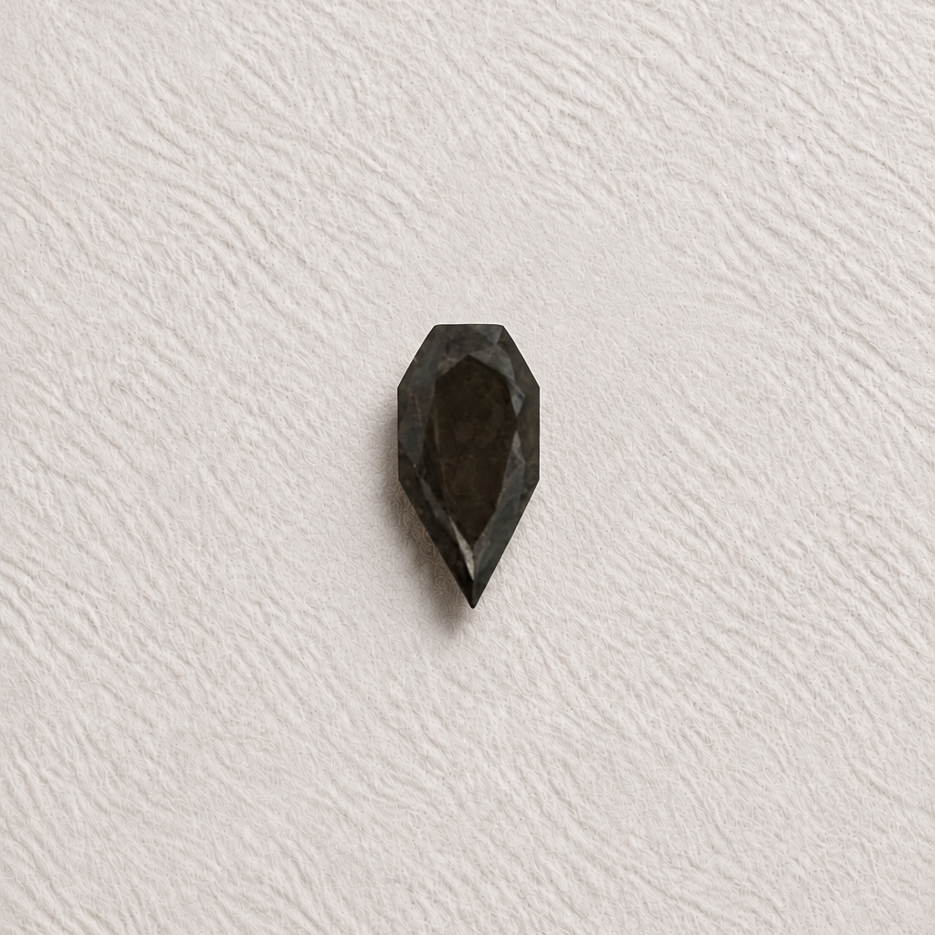 A single faceted dark gray gemstone with a teardrop or pear-like shape, centered on a textured off-white background.