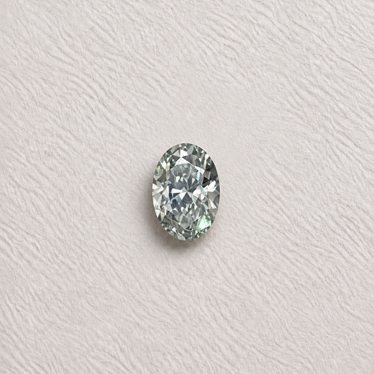A single oval-cut clear gemstone with light greenish-blue reflections, centred on a textured off-white background.